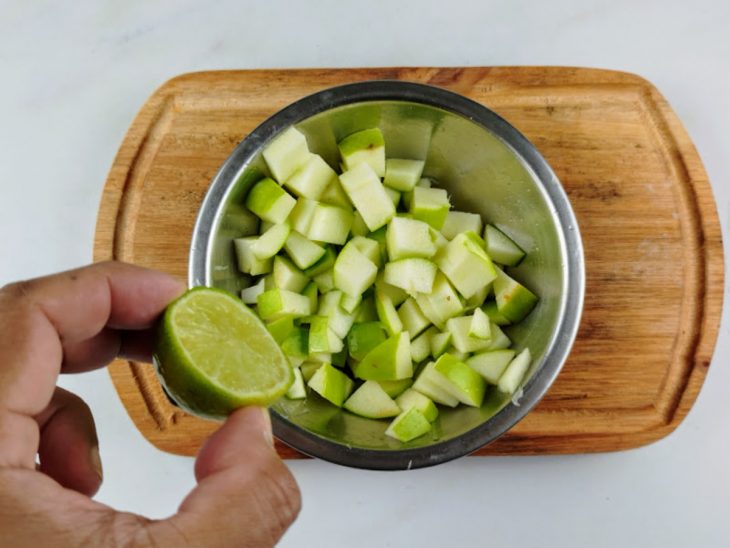 Limão espremido sobre os cubos de maçã-verde em uma tigela.