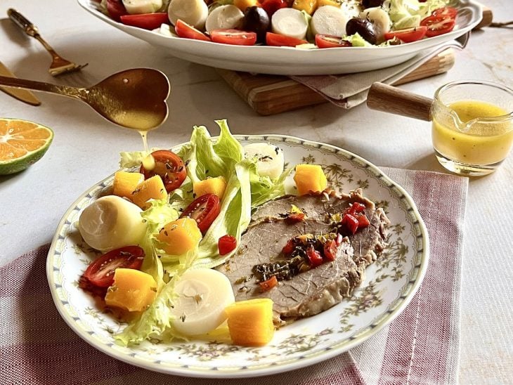 Porção da salada tropical em um prato com acompanhamentos.