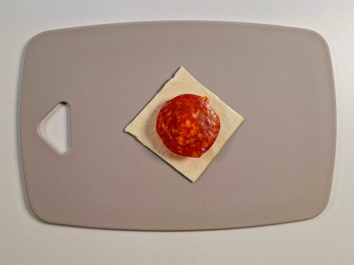Mussarela e pepperoni adicionados a massa.