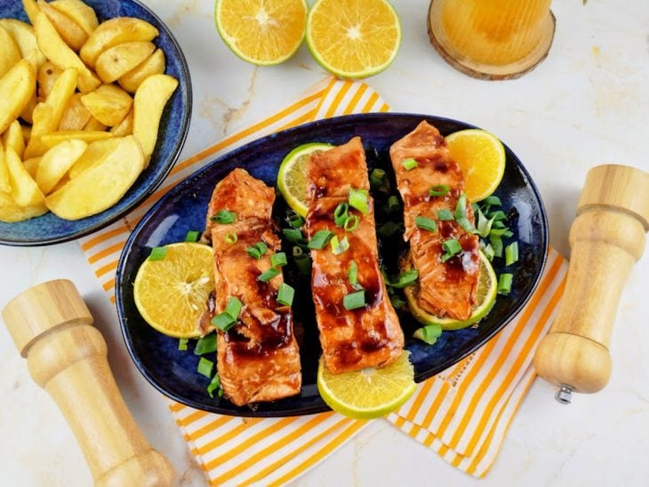 Salmão finalizado com rodelas de laranja e a cebolinha.