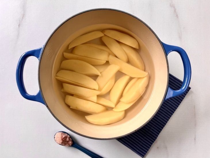 Panela com batatas cortadas cobertas com água para cozinhar.