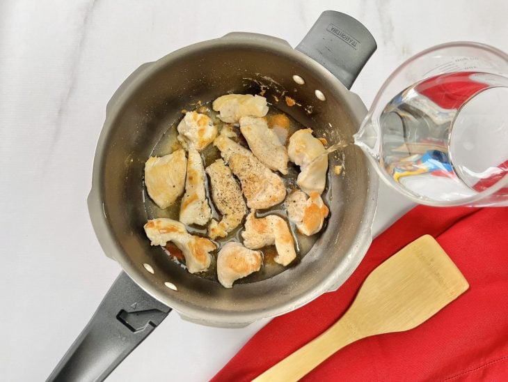Uma panela de pressão com frango e água.