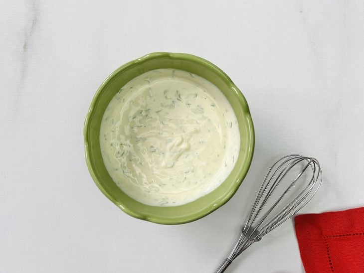 Um recipiente com creme de leite, maionese, cheiro verde, sal e pimenta-do-reino.
