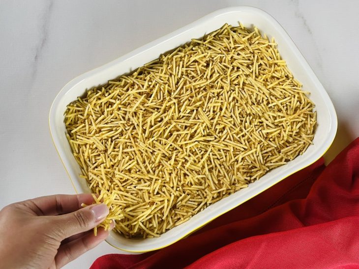 Uma travessa com salpicão e batata palha polvilhada por cima.