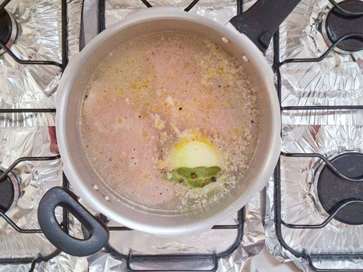 Frango sendo cozido na panela de pressão com temperos e cebola.