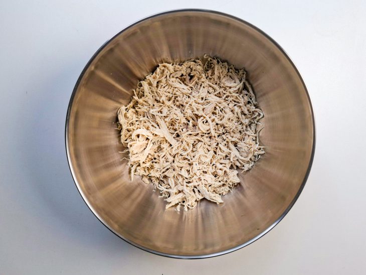 Frango cozido desfiado em uma tigela.