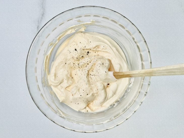 Maionese, requeijão, sal e pimenta-do-reino adicionados ao recipiente com alho.