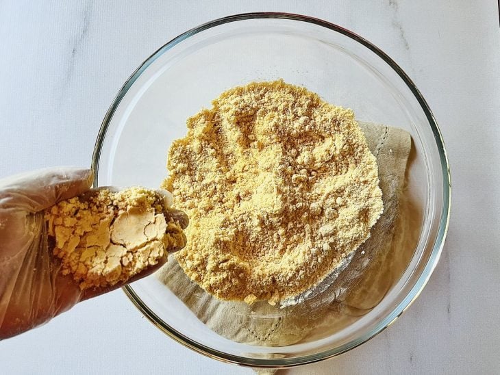Uma tigela com farinha de trigo, açúcar, sal e a mistura de manteiga derretida com colorau.