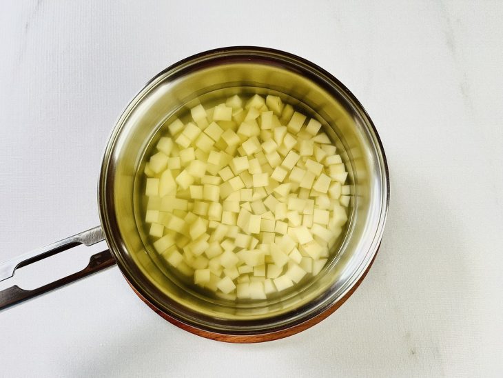 Uma panela com as batatas picadas, água e sal.