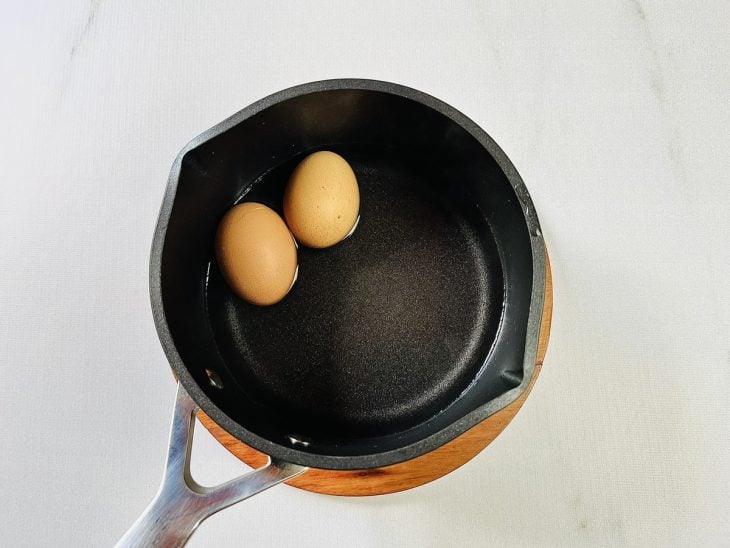 Uma panela com os ovos cozidos na água.