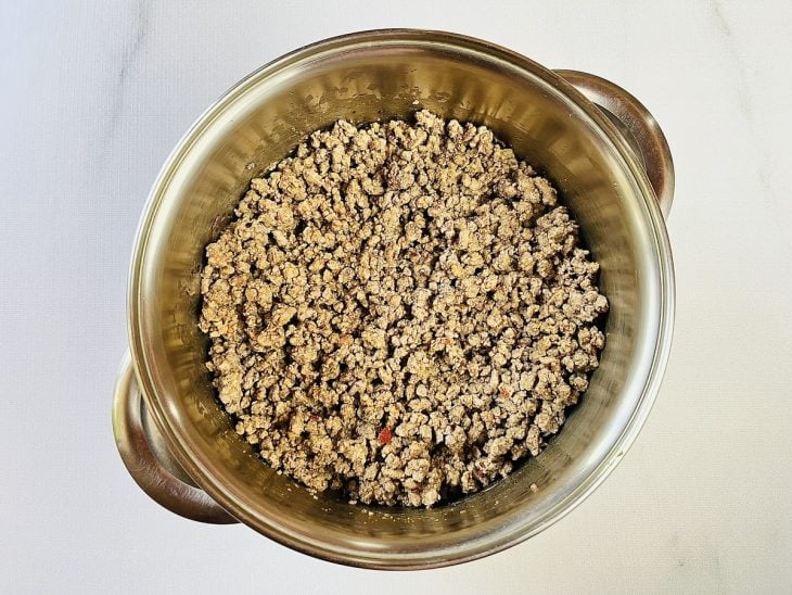 Uma panela com azeite, cebola, alho e carne moída.