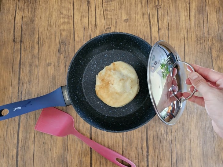 Frigideira com o pão sírio recheado sendo tampada.