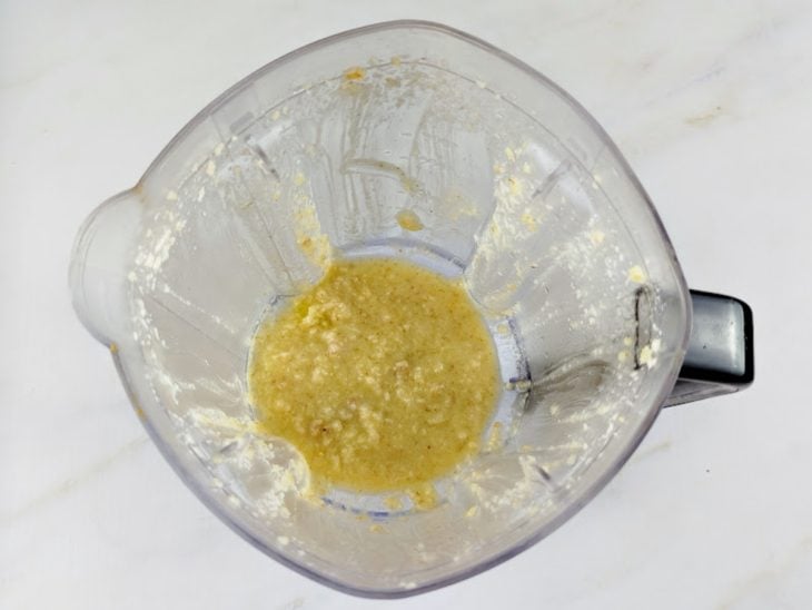 Um liquidificador com alho, parmesão, nozes e azeite.