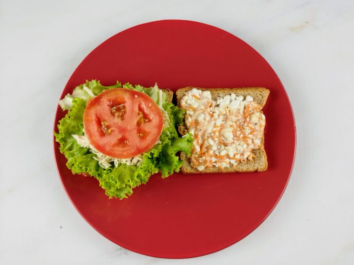 Um prato com os pães recheados com a pastinha, frango, tomate, alface.