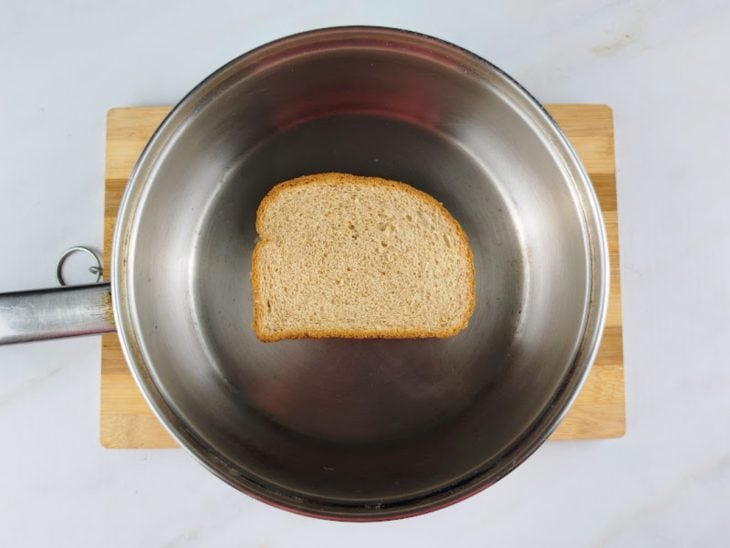 Uma frigideira contendo uma fatia de pão com manteiga.