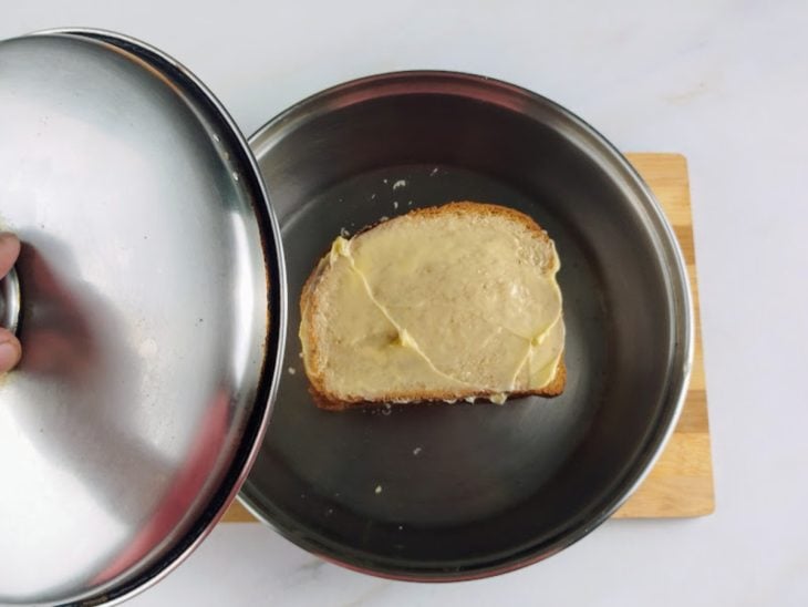 Frigideira com o sanduíche sendo tampada.