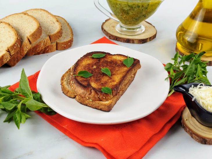 Um prato contendo sanduíche de frigideira com molho pesto e parmesão.