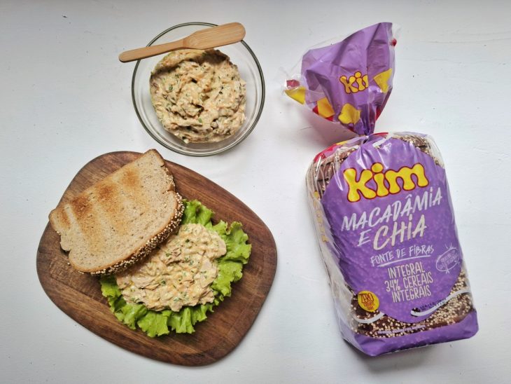 Fatia de pão sendo recheada com alface e a mistura de atum.