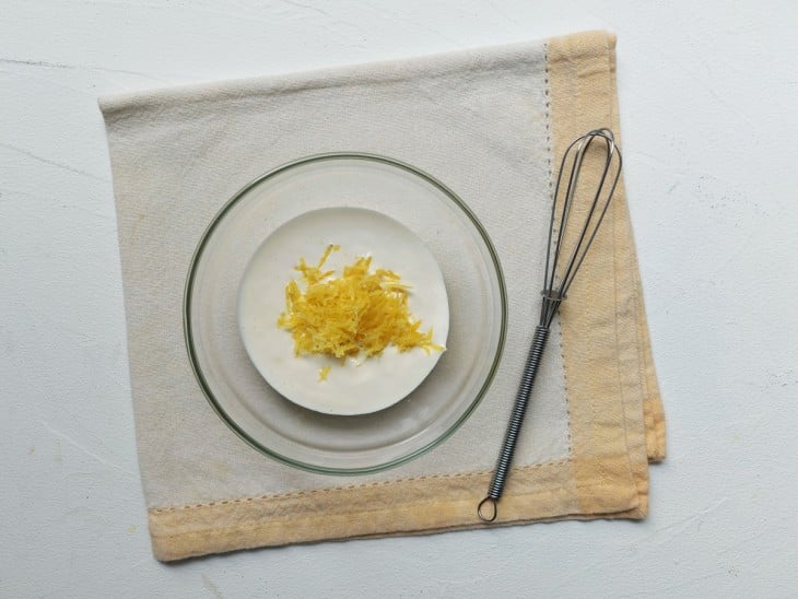 Creme de leite e raspas de limão em uma tigela transparente.