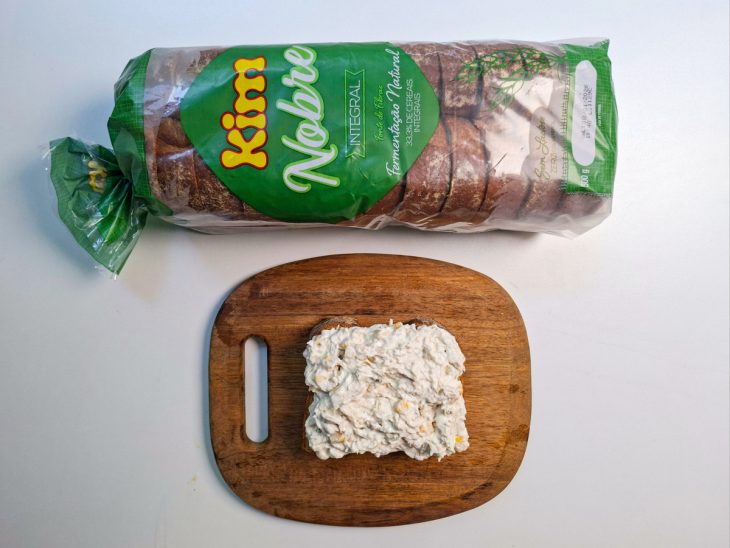 Recheio de frango sendo espalhado sobre a fatia de pão integral.