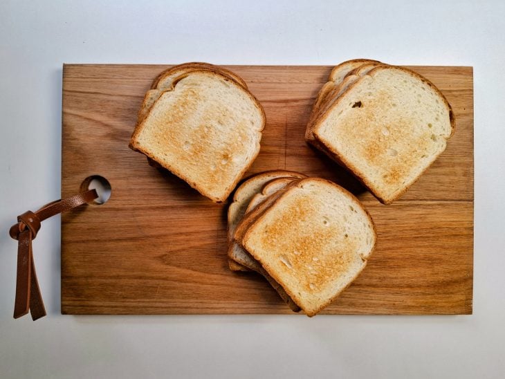 Pães de forma tostados levemente sobre uma tábua de cozinha.