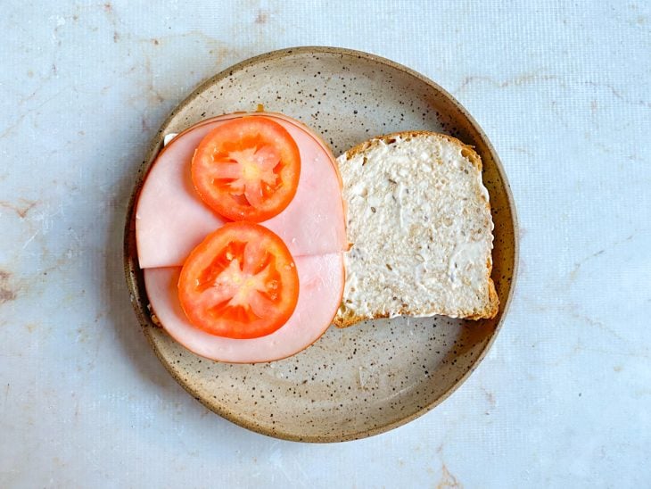 Rodelas de tomate acomodadas sobre as fatias de peito de peru.