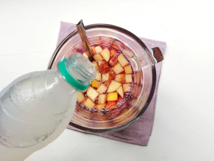 Uma jarra contendo as frutas, os sucos e o refrigerante.