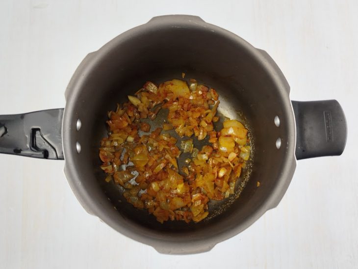 Cebola dourando em óleo na panela de pressão.