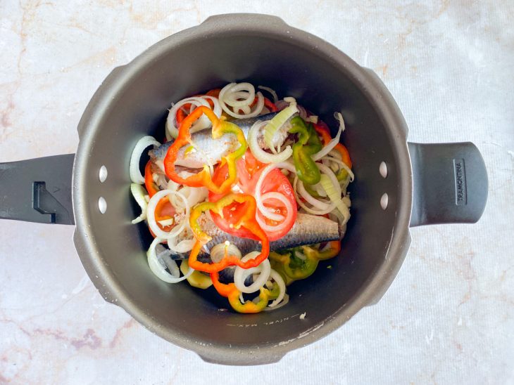 Na panela, mais uma camada de sardinha, e outra com os legumes.