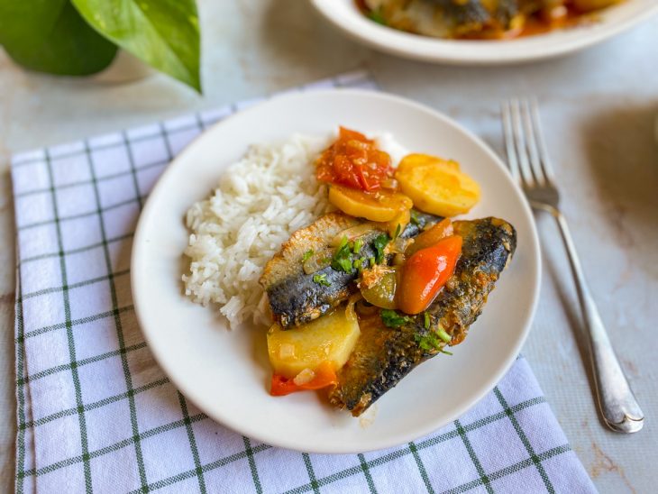 Sardinha pronta, servida em prato com arroz branco.