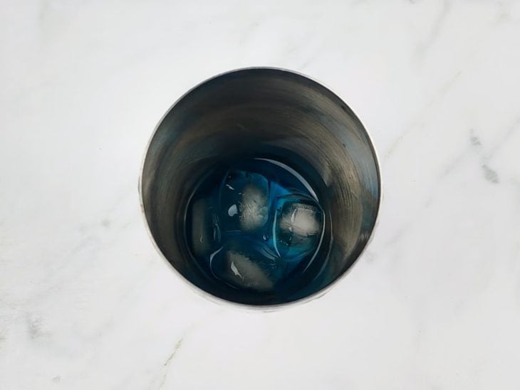 Gelo, vodka e curaçau blue em uma coqueteleira.