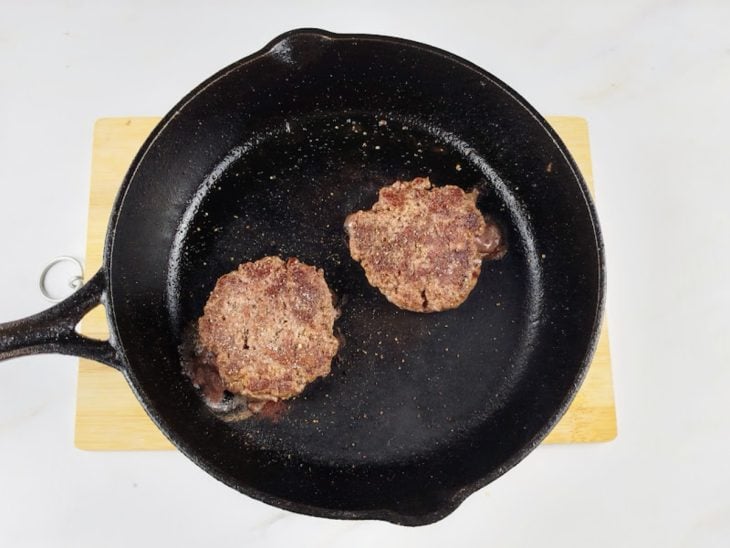 Hambúrgueres com crostinha dourada na frigideira.