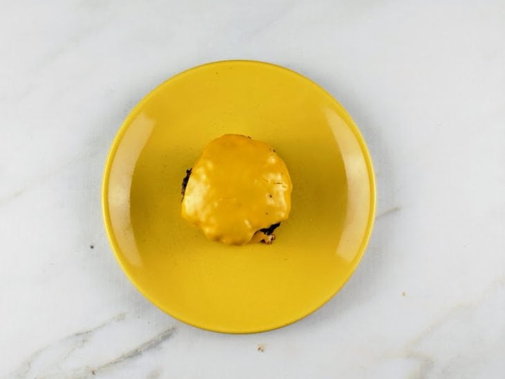 Hambúrgueres reservados em um prato redondo amarelo.