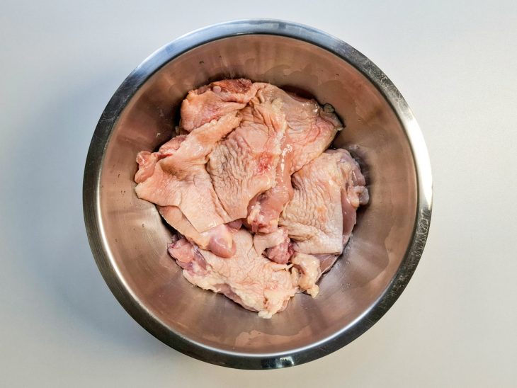 Pedaços de frango temperados com limão e sal em uma tigela.