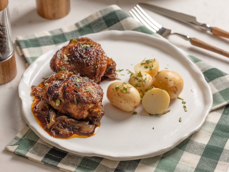 sobrecoxa servida com batata grelhada e finalizada com salsinha.