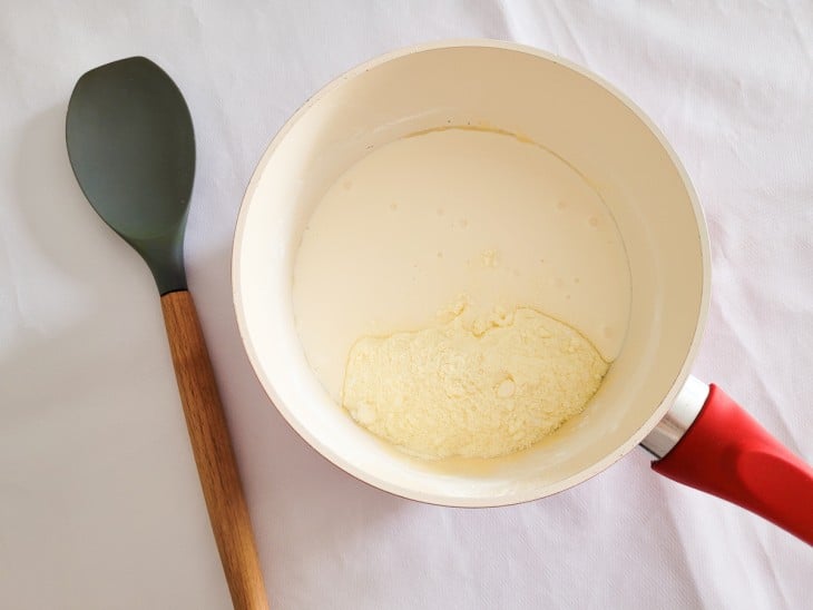 Uma panela com leite condensado, amido de milho, creme de leite e leite em pó.