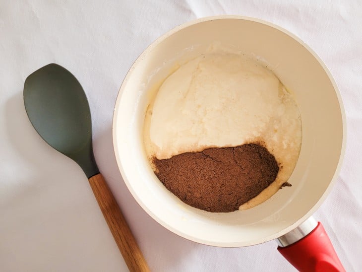 Uma panela com leite condensado, amido de milho, creme de leite e chocolate em pó.