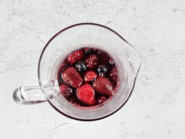 Jarra com frutas vermelhas, xarope grenadine, suco dos limções e chá.