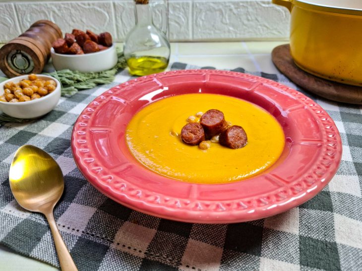Sopa creme de grão-de-bico servida em um prato individual rosa.