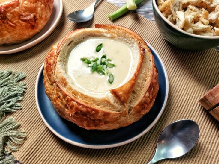 Um prato contendo sopa cremosa com fondue no pão italiano.