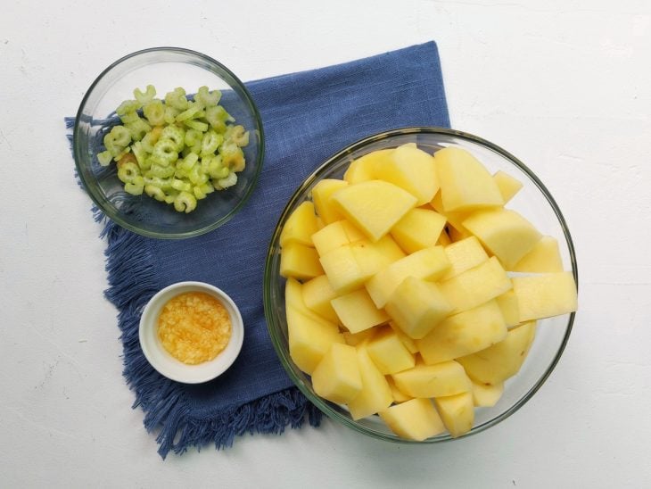 Recipientes com salsão, batata e alho picados.