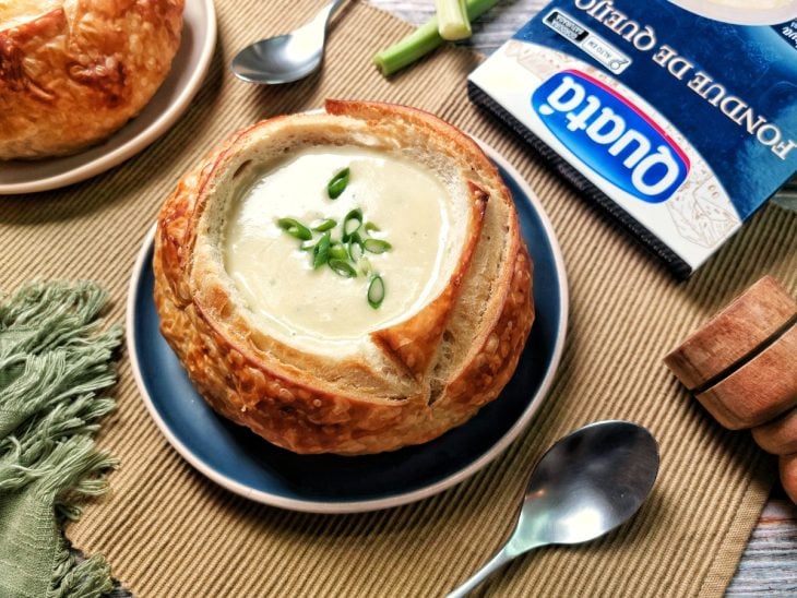 Um prato contendo sopa cremosa com fondue no pão italiano.