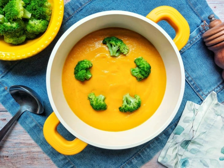 Uma panela contendo sopa cremosa de brócolis com cenoura.