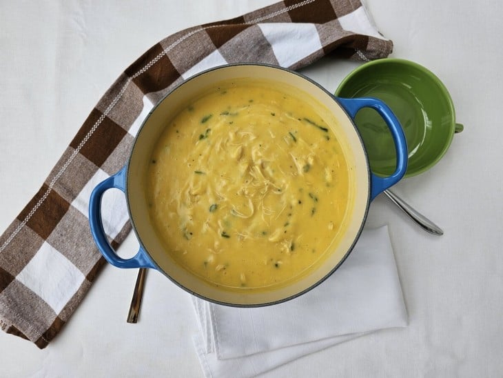 Uma panela contendo sopa cremosa de mandioquinha com frango desfiado.