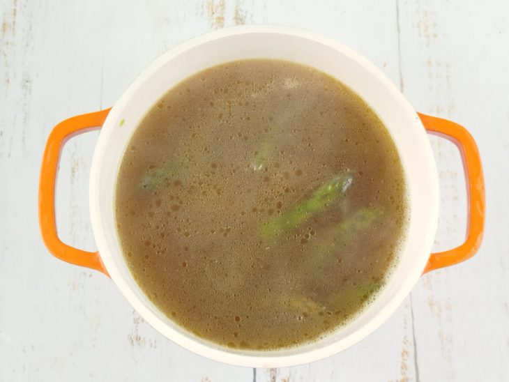 Aspargos inteiros sendo adicionados ao caldo coado na panela.