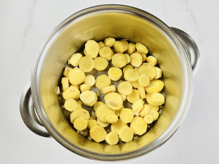 Na panela, as batatas cortadas em rodelas são adicionadas.