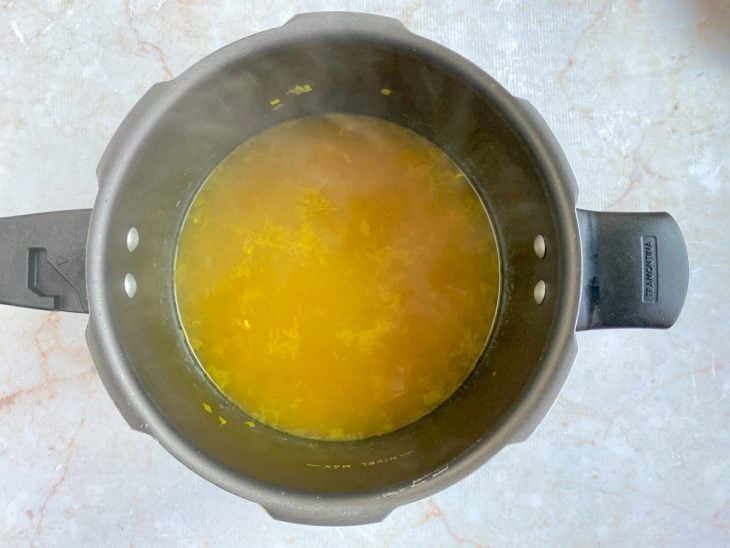 Panela de pressão com o frango, alho, alho-poró, cebola, cenoura, água e temperos.