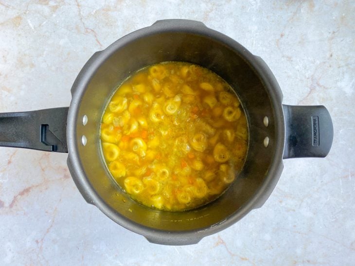 Macarrão adicionado na panela de pressão com os outros ingredientes da sopa.
