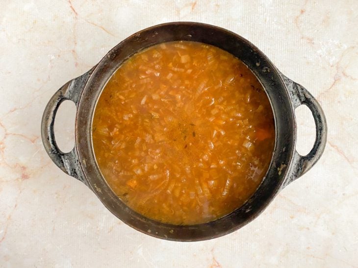 Caldo de carne e temperos adicionados na panela.