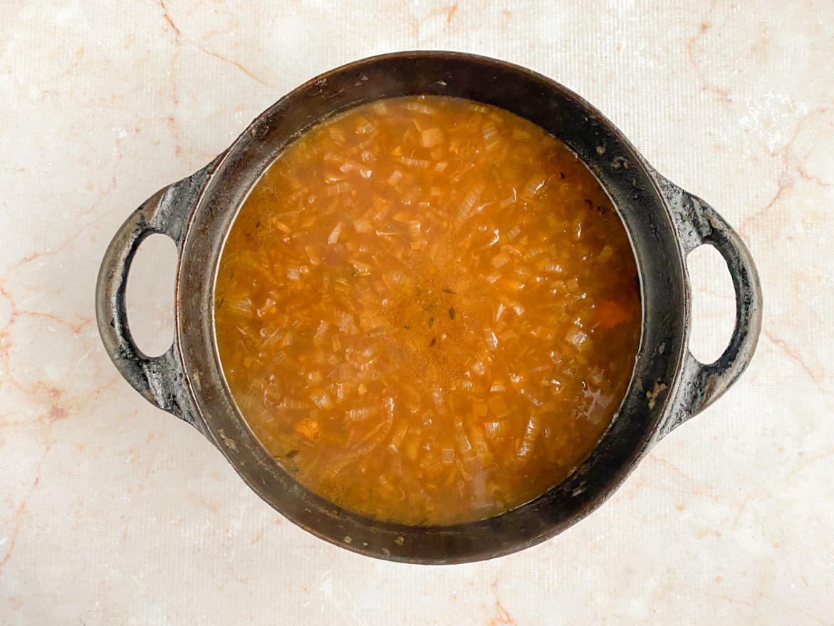 Caldo de carne e temperos adicionados na panela.